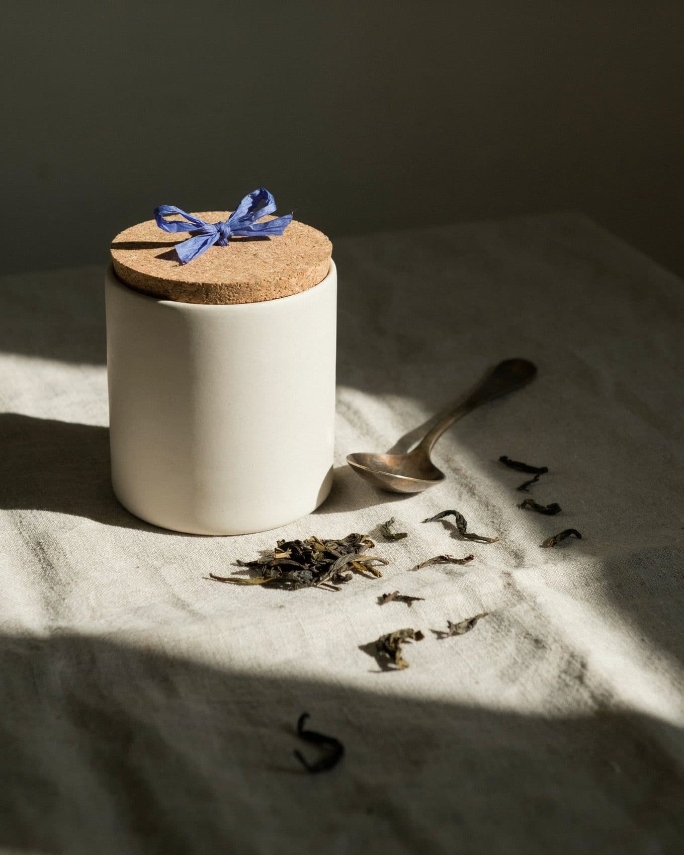 Feed post of a tea canister on raw linen with tea leaves